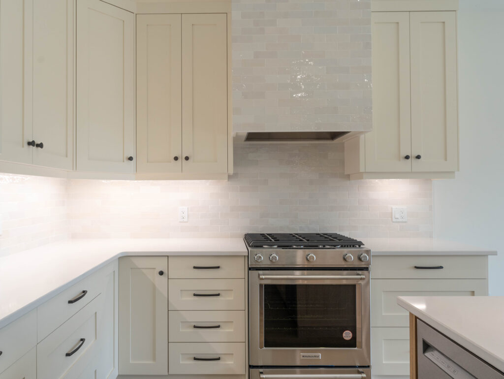 White cabinets in kitchen designed and installed by Sarnia Cabinets. Faux white brick backsplash and black knobs and handles.