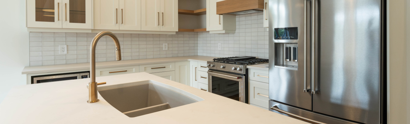 Classic kitchen by Sarnia Cabinets. Features white cupboards, white tiles and white countertop with gold accents.