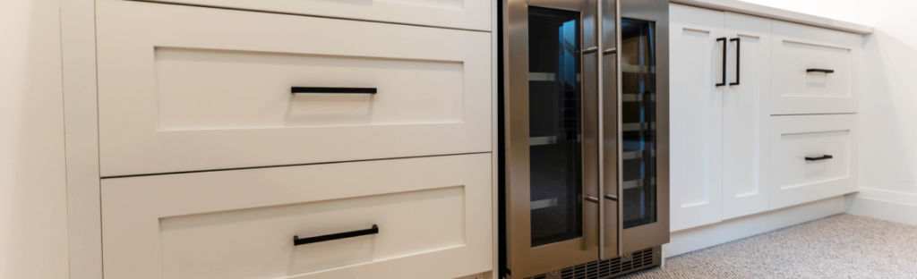 White custom bar by Sarnia Cabinets. Black handles and wine fridge.