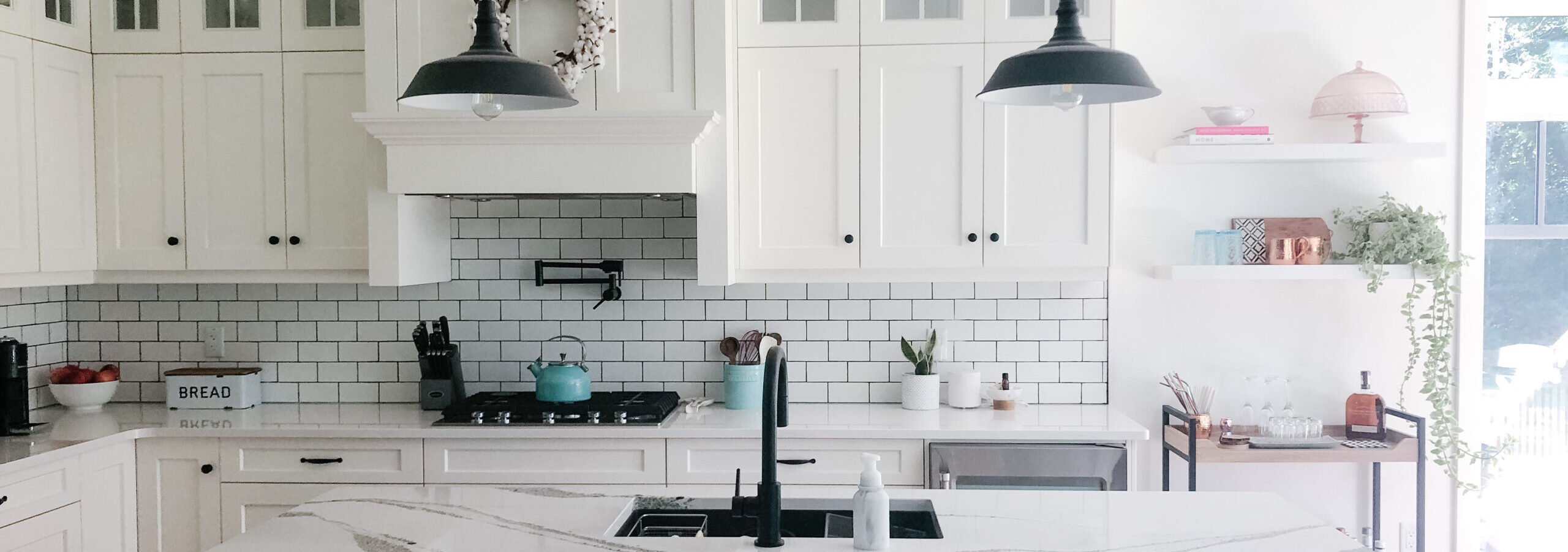 Clean white cabinets with white subway tiles and a white countertop create a beautiful simple kitchen space.