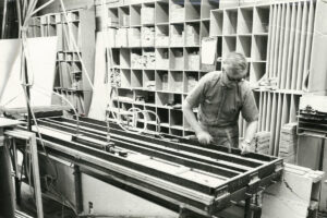 Black and white photo of a Sarnia Cabinets employee using machinery to create custom cabinet doors.