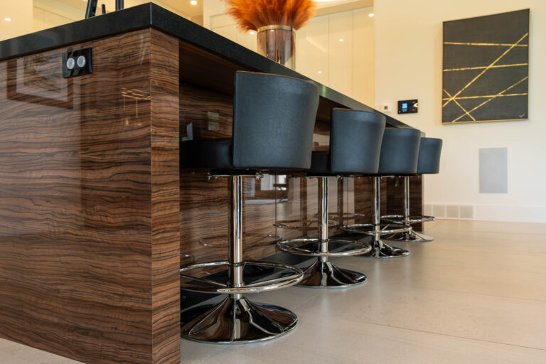Glossy wood grain kitchen island with black stools by Sarnia Cabinets.